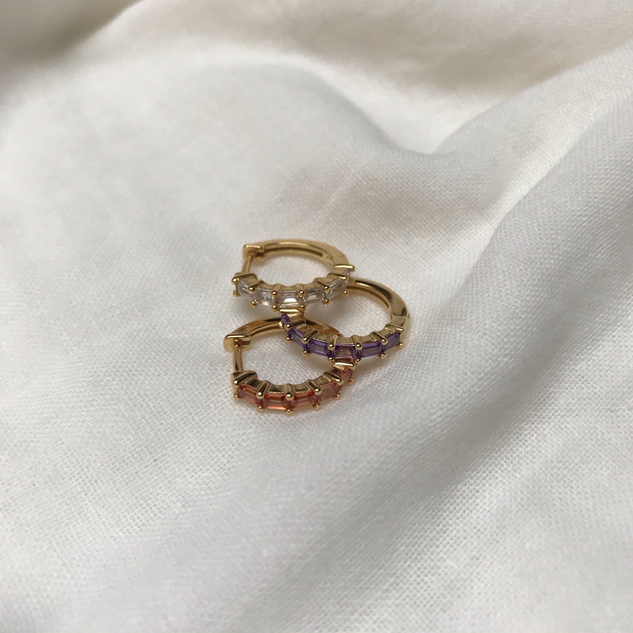 Aros pequeños combinables con otros pendientes, estilo moderno.