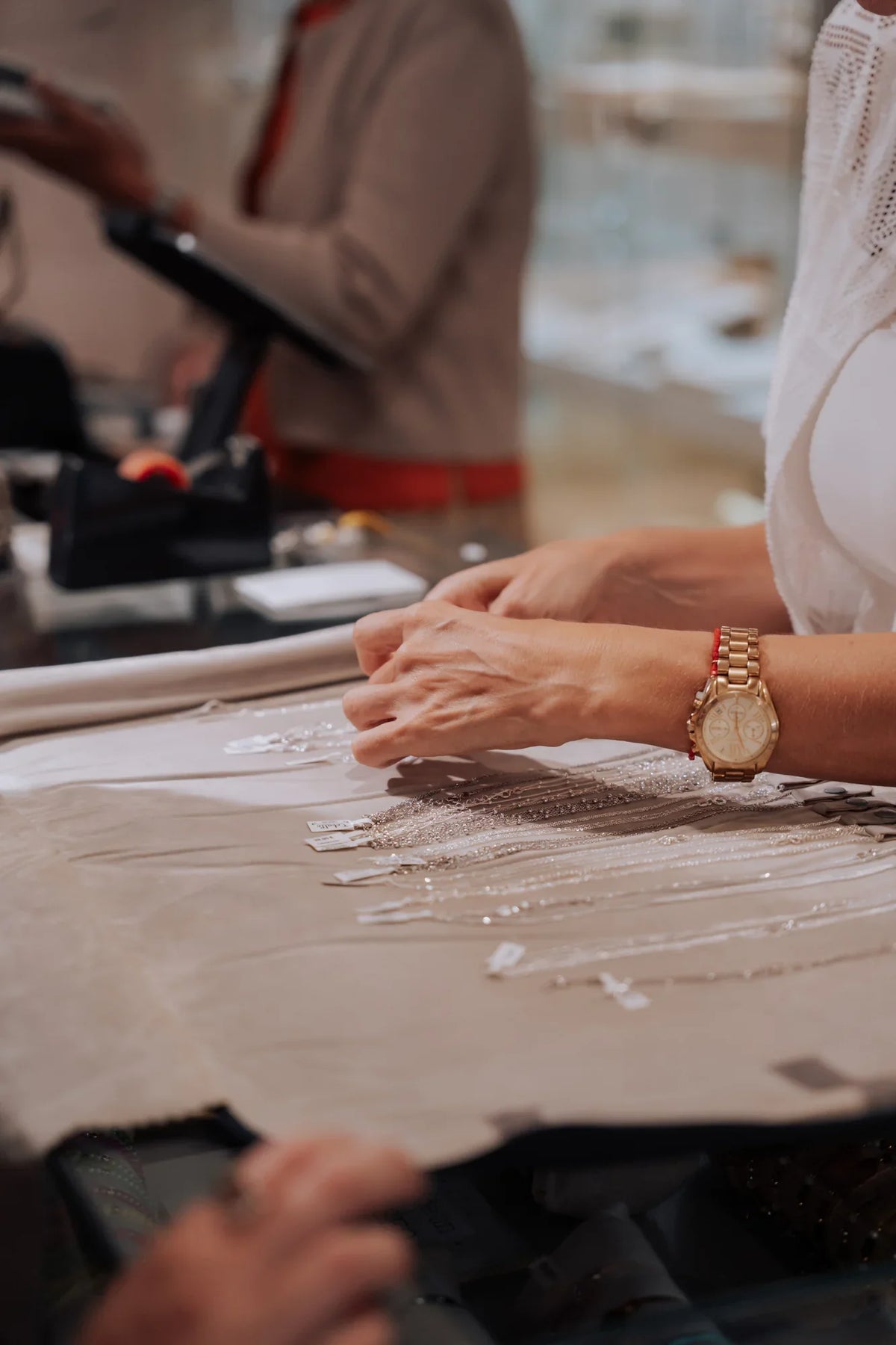 Manos eligiendo collares finos dorados sobre una tela, en la tienda Cobalto Accesorios de Valencia`