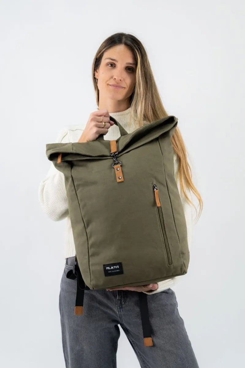 Mujer sosteniendo mochila verde de diseño sostenible con cierre enrollable y detalles en cuero, ideal para el día a día, disponible en Cobalto Accesorios