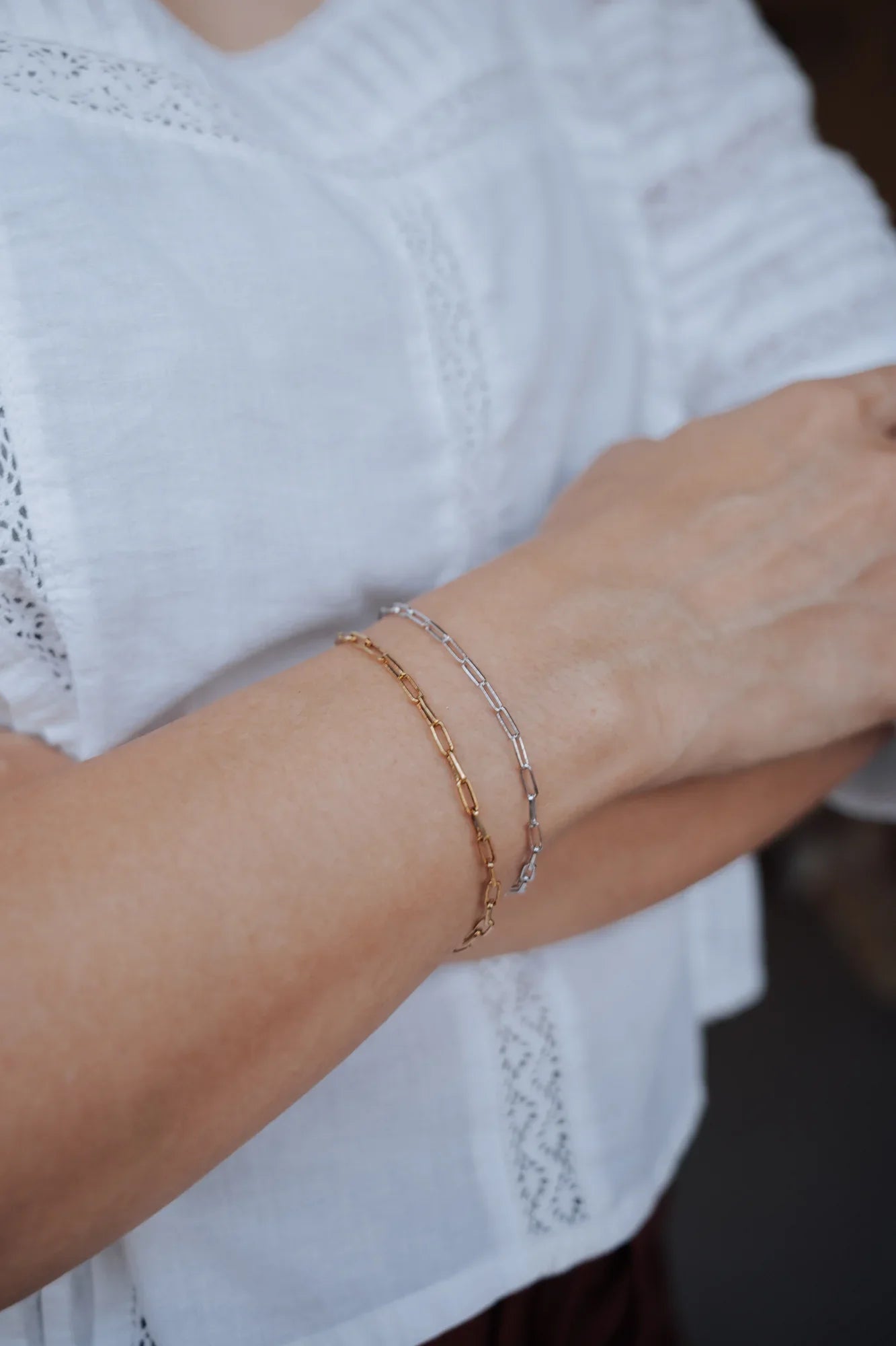 Pulsera de eslabones en plata de ley 925 con baño de oro puesta en la muñeca, sobre blusa blanca