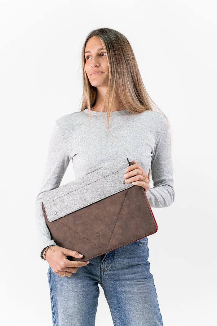 Mujer sosteniendo funda para portátil de 15.6'' en tonos marrón y gris con diseño elegante y funcional, disponible en Cobalto Accesorios.