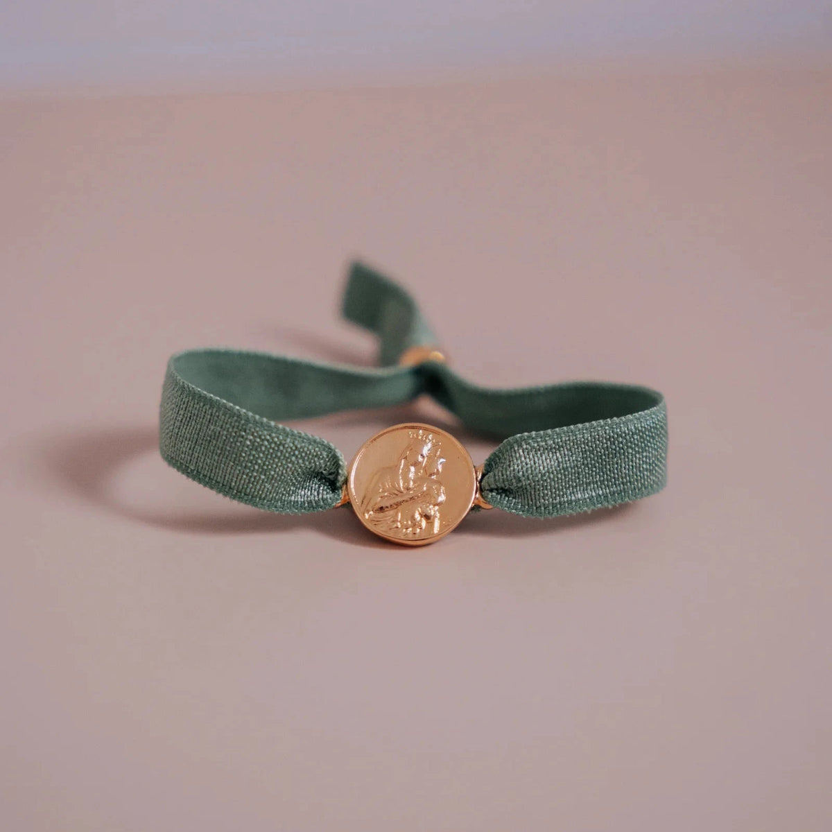 Pulsera escapulario dorada con cinta elástica verde y medalla de la Virgen del Carmen
