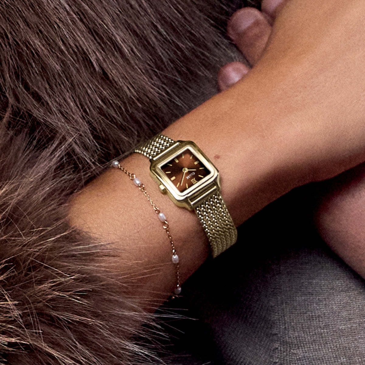 Reloj Cluse Gracieuse Mini dorado de esfera marrón en la muñeca, con abrigo de pelo - Cobalto Accesorios