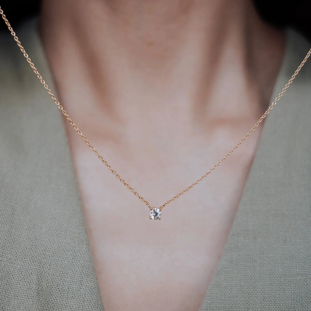 Collar de circonita engarzada en dorado sujetado en primer plano con cuello de modelo detrás