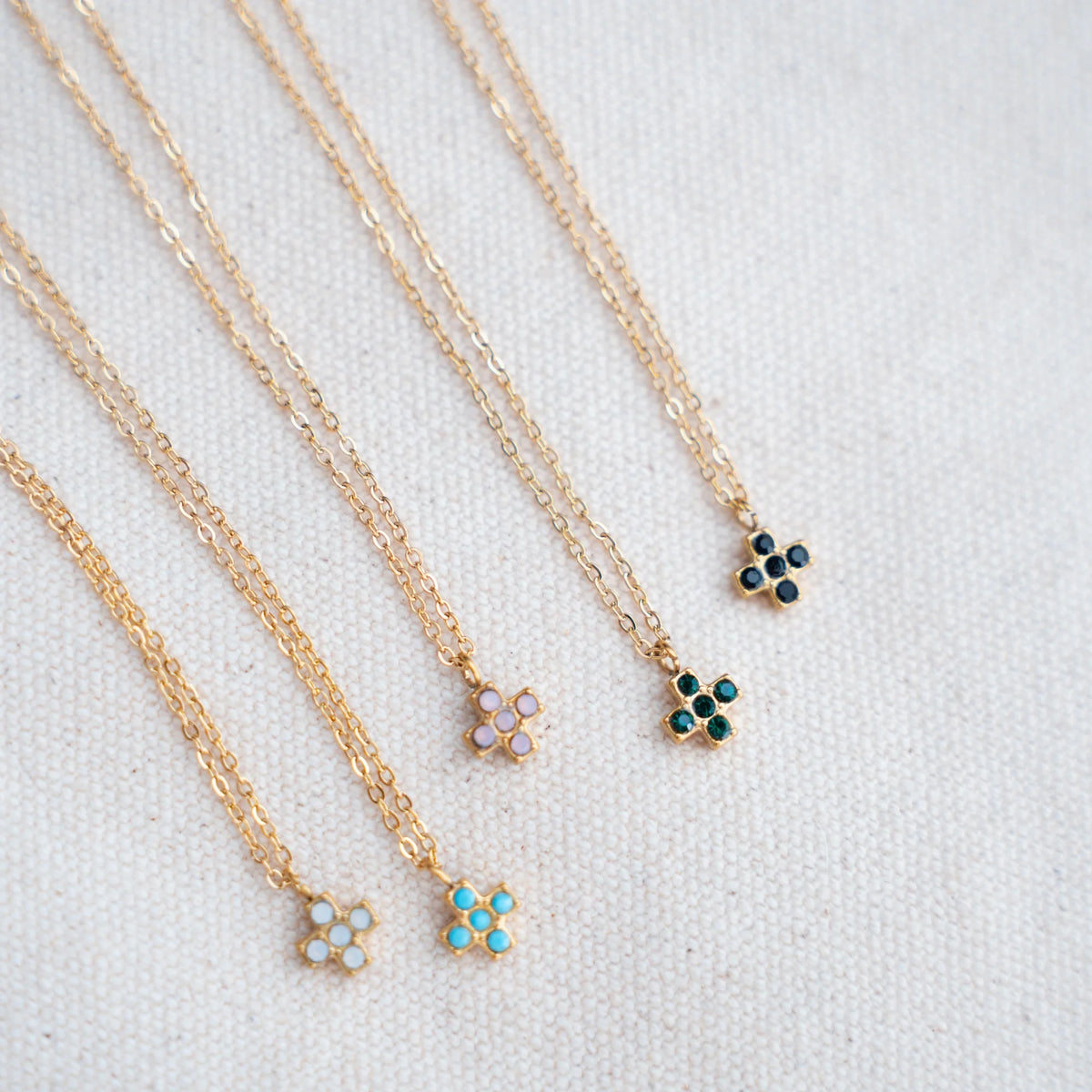 Collares de cruz cuadrada con circonitas en siete colores sobre lino