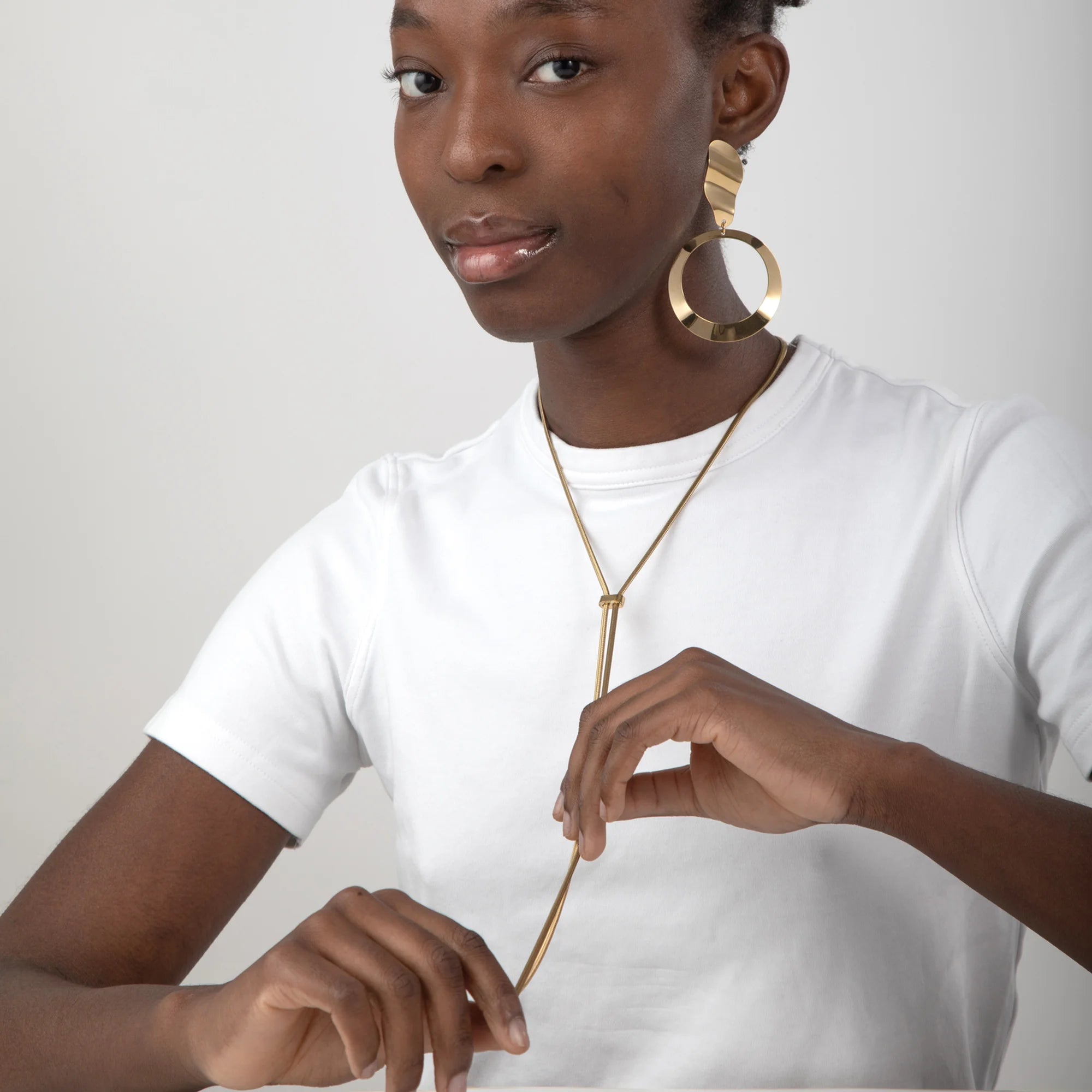 Modelo llevando collar cuerda ajustable dorado sobre camiseta blanca