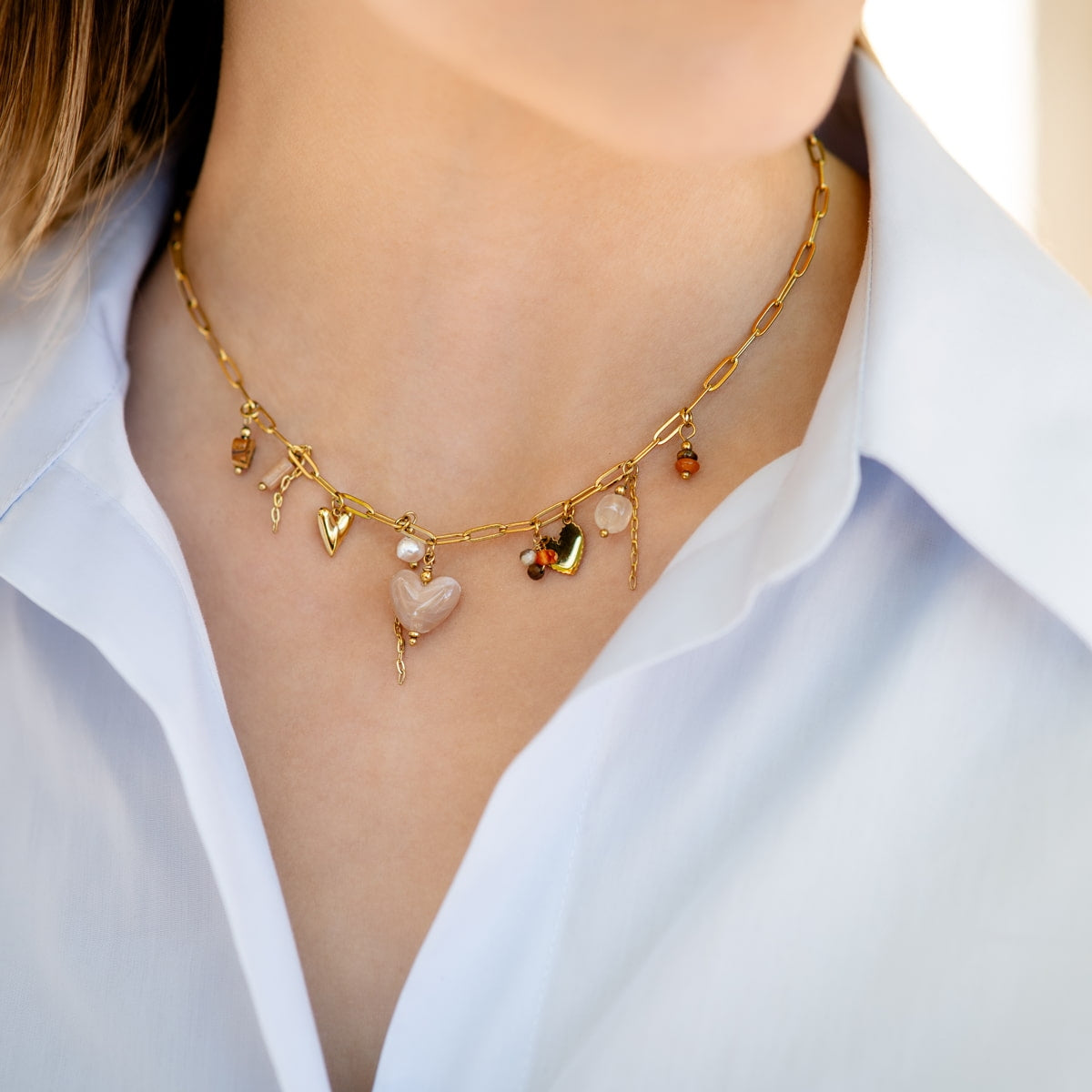 Detalle de modelo llevando collar Terra di Amore con charms de corazones y estilo boho