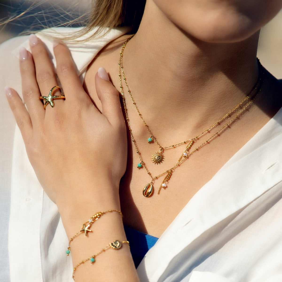 Modelo llevando collar dorado con colgante de sol junto otras piezas de la colección