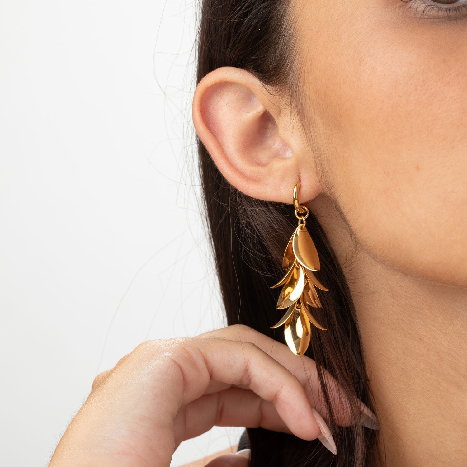 Pendientes dorados de aro con hojas colgando en acero inoxidable 316L, mostrados puestos en la oreja, diseño elegante y ligero, Cobalto Accesorios Valencia