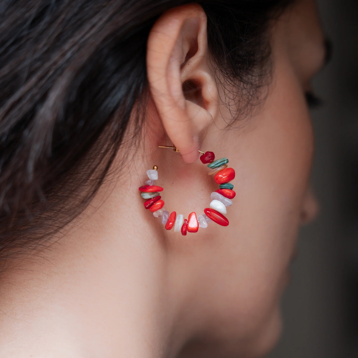 Pendiente semi aro con piedras rojas y blancas puesto en la oreja, de perfil