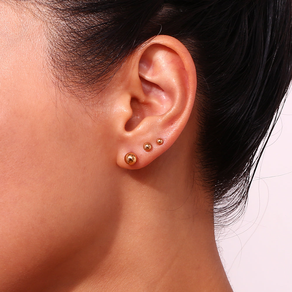 Pendientes bola dorados de acero inoxidable de 18K en oreja femenina, estilo minimalista – Cobalto Accesorios Valencia