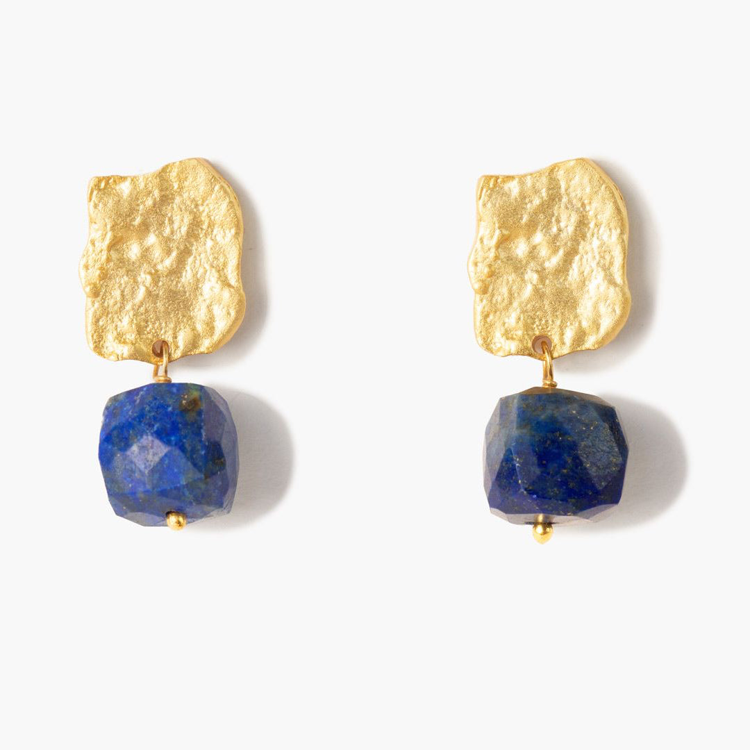Pendientes Bruma con acabado dorado texturizado y piedra lapislázuli facetada en azul intenso, sobre fondo blanco con sombra suave.