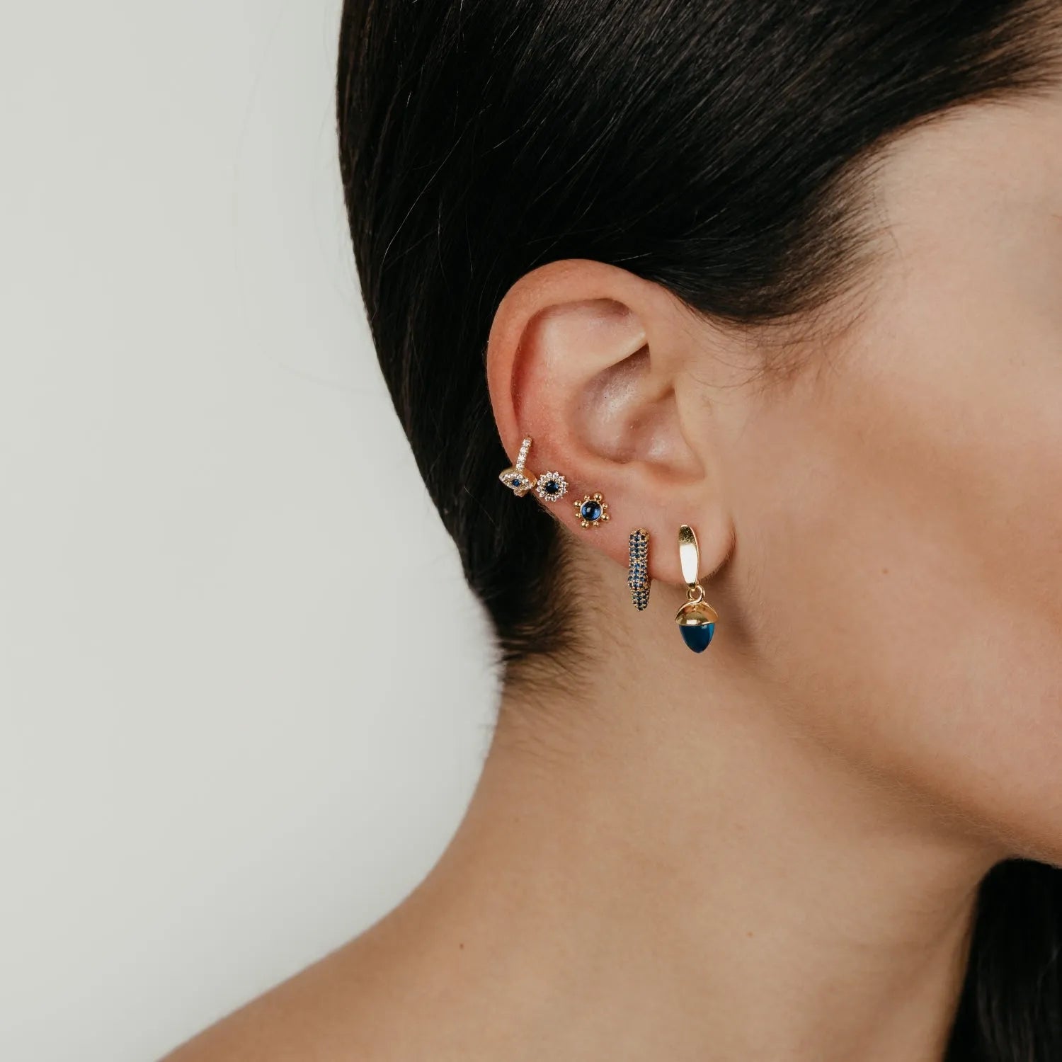 Detalle de pendientes flor con circonitas de colores, pieza pequeña y luminosa