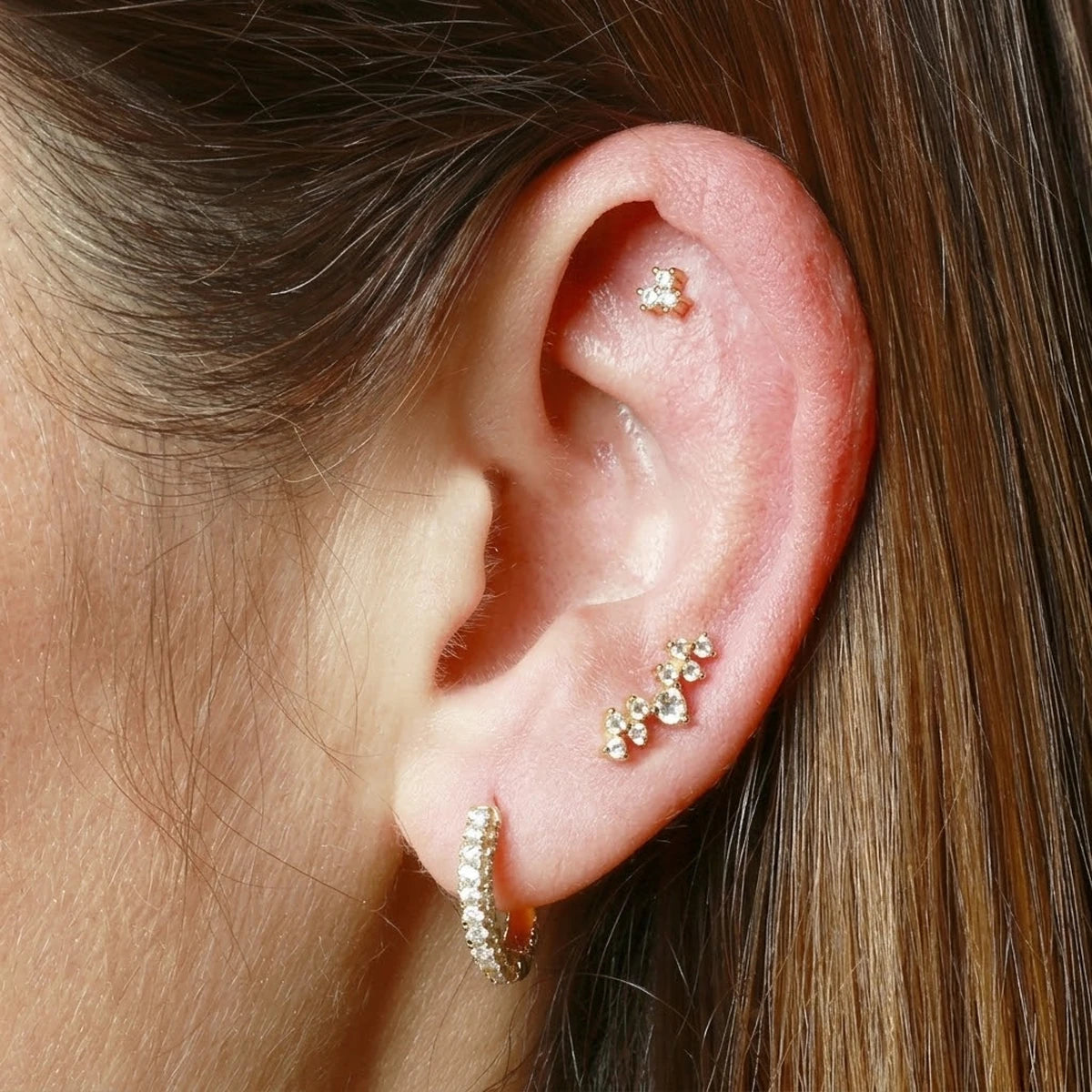 Piercing Trébol 3 Circonitas dorado con circonitas blancas, puesto en la parte alta de la oreja
