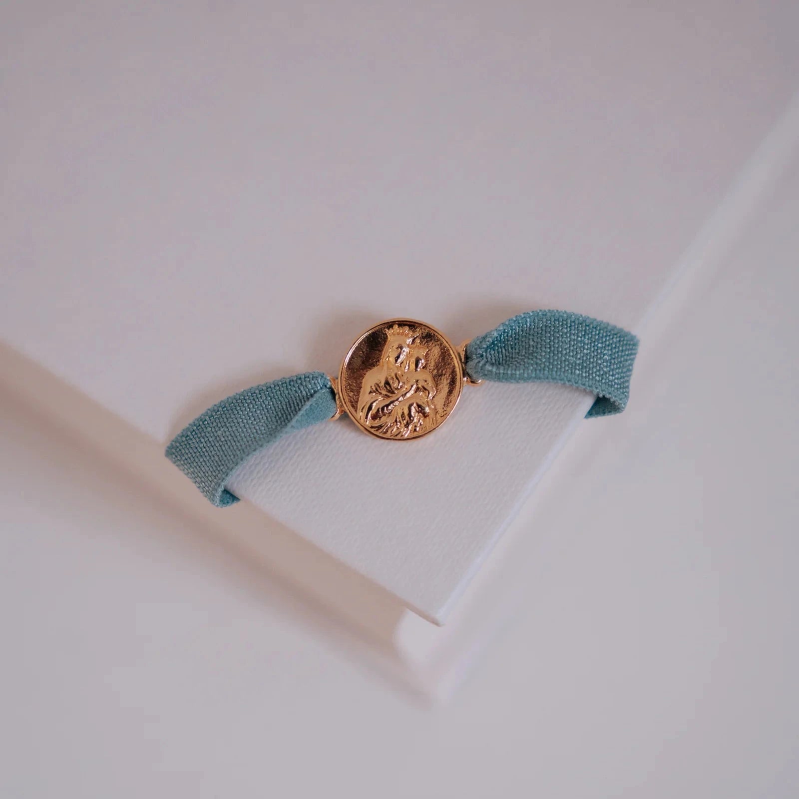 Pulsera escapulario con cinta elástica azul apoyada sobre un libro