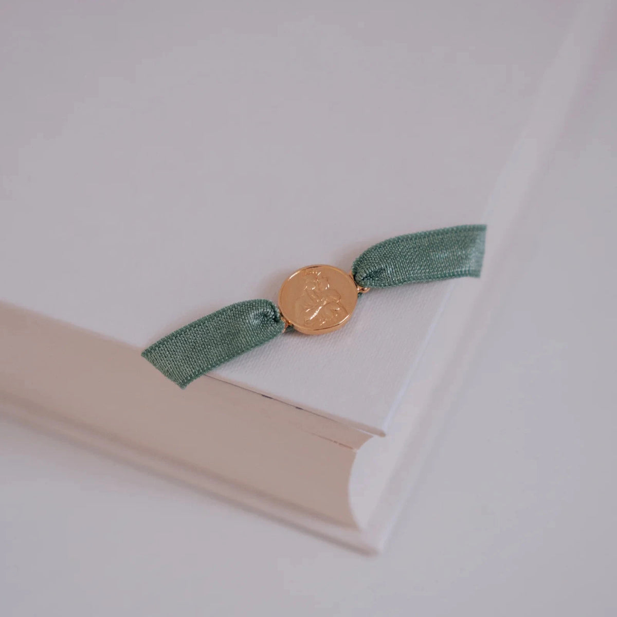 Pulsera escapulario con cinta elástica verde apoyada sobre un libro