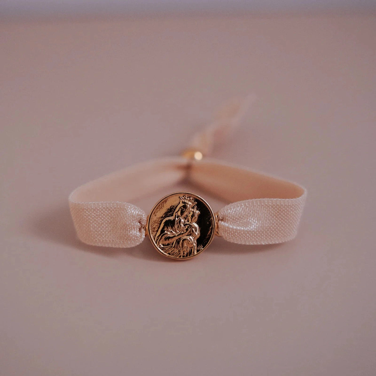 Pulsera escapulario dorada con cinta elástica nude