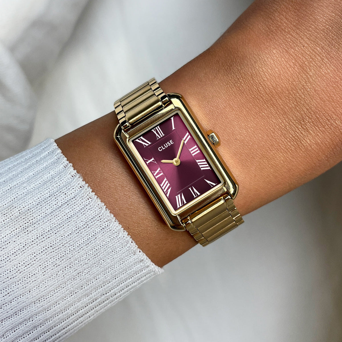 Reloj Cluse Belisenna dorado con esfera rojo vino y números romanos, llevado en la muñeca - Cobalto Accesorios