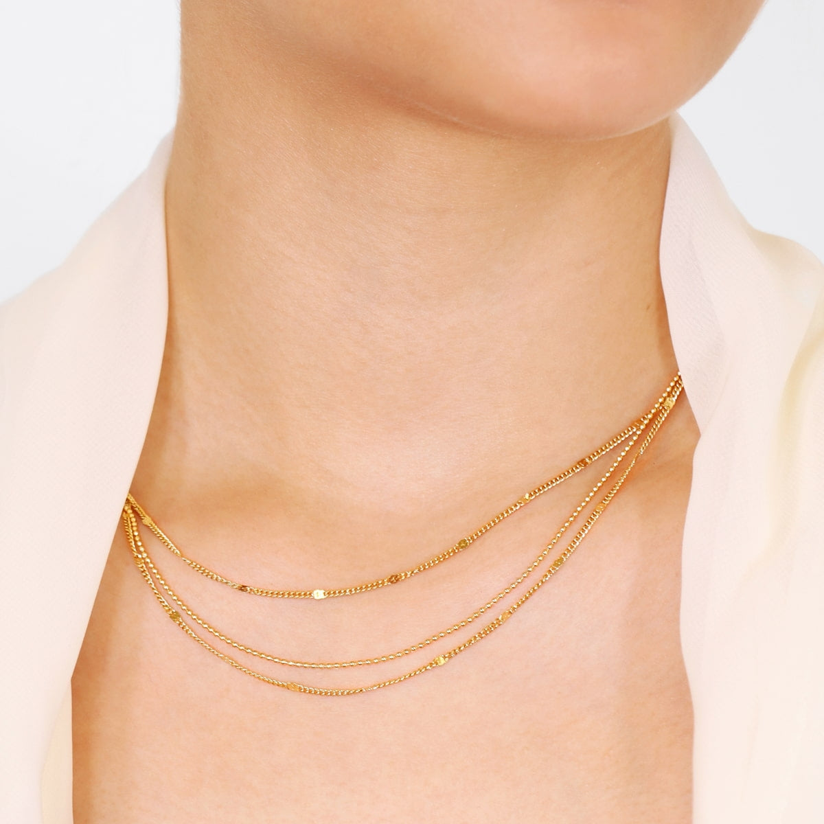 Mujer luciendo el collar Rainfall Lumira dorado con triple cadena de acero