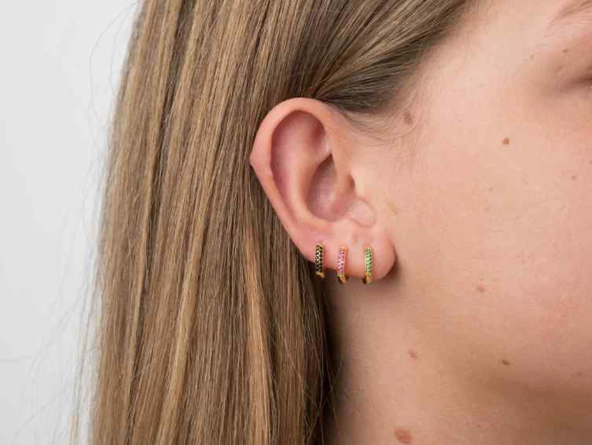 Modelo con 3 pendientes de aro ancho con circonitas puestos en la oreja.