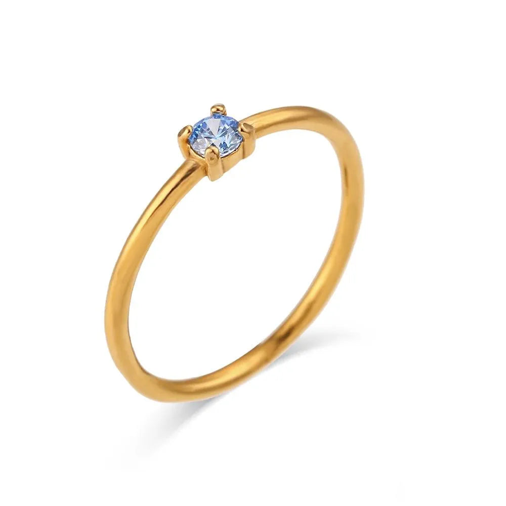 Anillo con circonita aguamarina engarzada en acero dorado, diseño elegante
