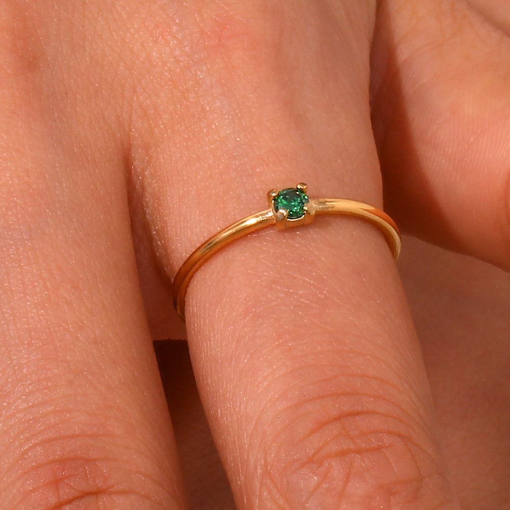 Modelo luciendo anillo con circonita verde engarzada en acero inoxidable dorado, diseño elegante y moderno de Cobalto Accesorios.