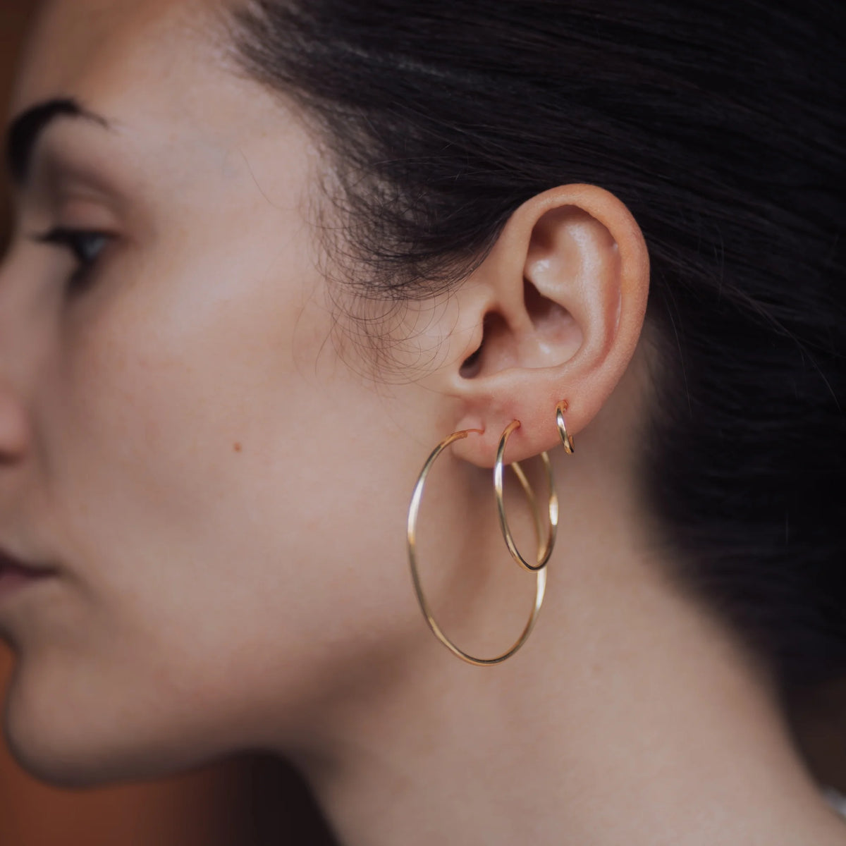 Aros dorados de 30 y 45 mm puestos en la oreja