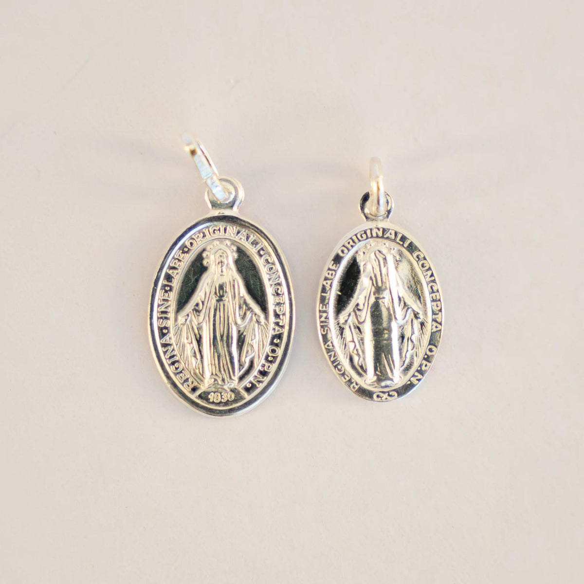 Las dos tallas de la Milagrosa de plata juntas, 16 x 11 y 21 x 13 mm