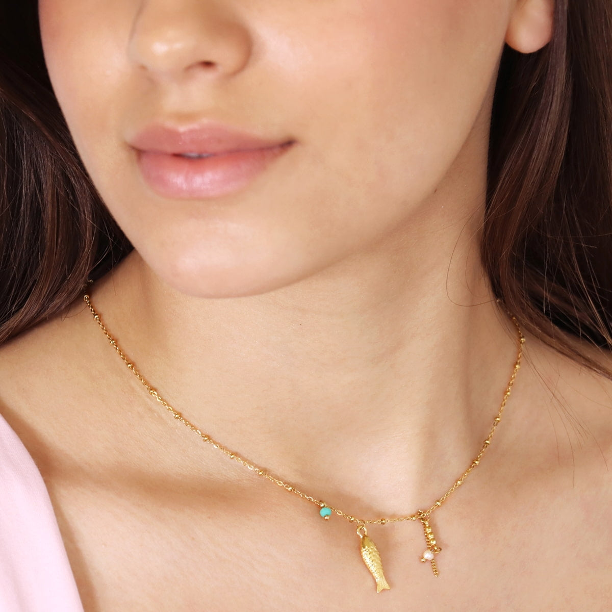 Modelo luciendo collar dorado con cola de pez
