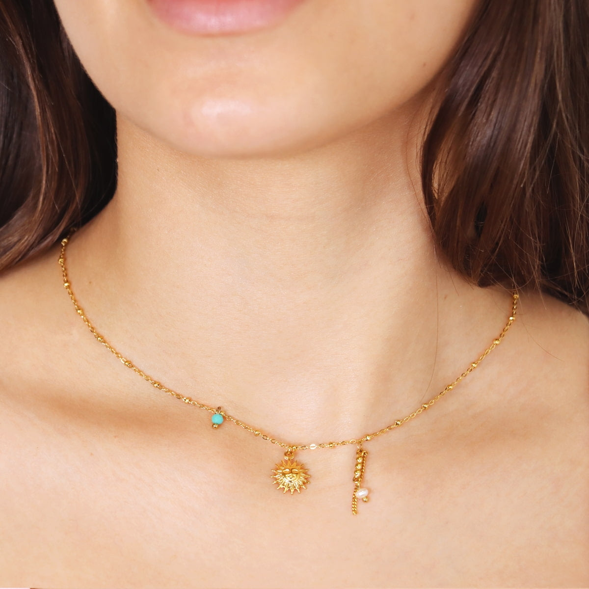 Modelo llevando collar dorado con colgante de sol
