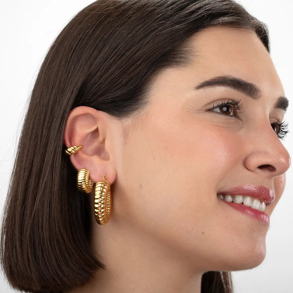 Modelo luciendo el ear cuff croissant dorado de acero inoxidable con baño de oro 18K, diseño trenzado moderno y elegante de Cobalto Accesorios Valencia.