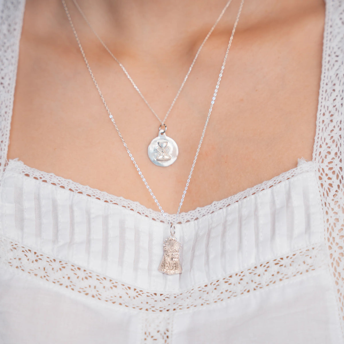 Medalla de la Virgen de los Desamparados en plata puesta en cadena corta, con la figura de la Virgen en una cadena más larga