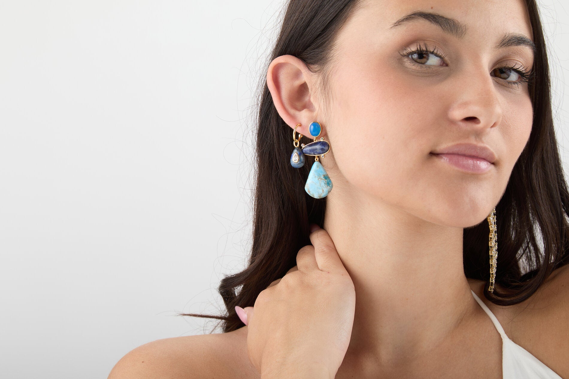Modelo llevando los pendientes Apatita Atlántica con piedras naturales azules y acabado dorado