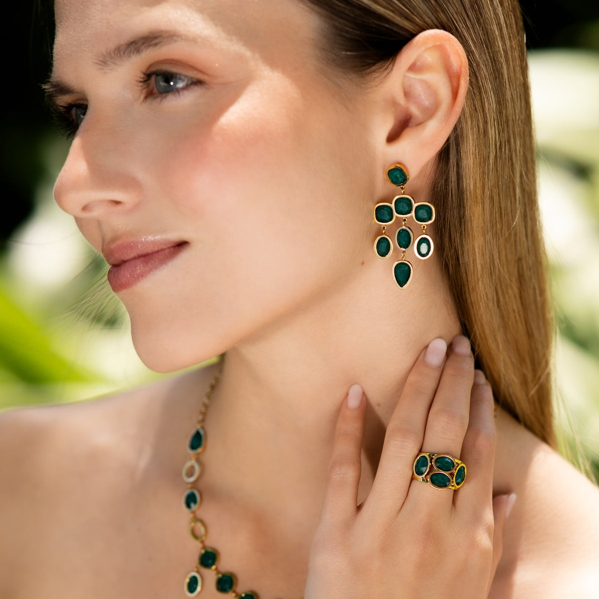 Modelo con pendientes de cristales verdes y base dorada
