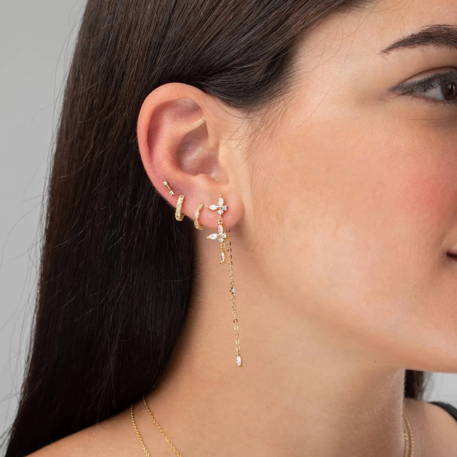 Detalle de pendientes largos con circonitas amatista o verdes, pieza elegante y luminosa