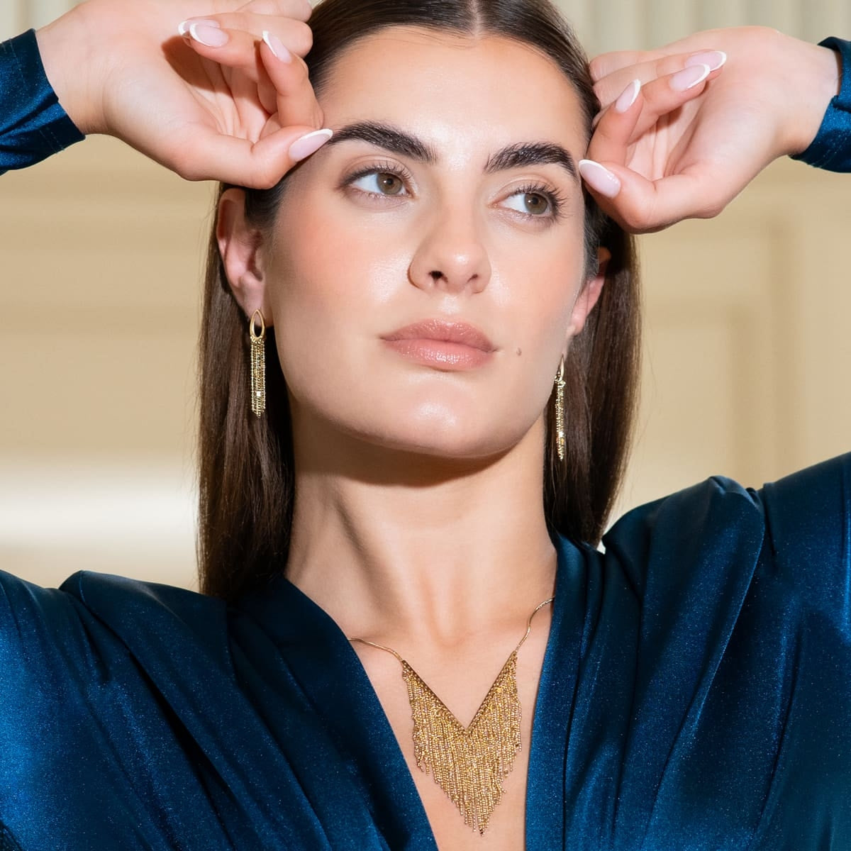 Pendientes dorados largos lucidos por modelo con vestido azul, estilo elegante de noche.