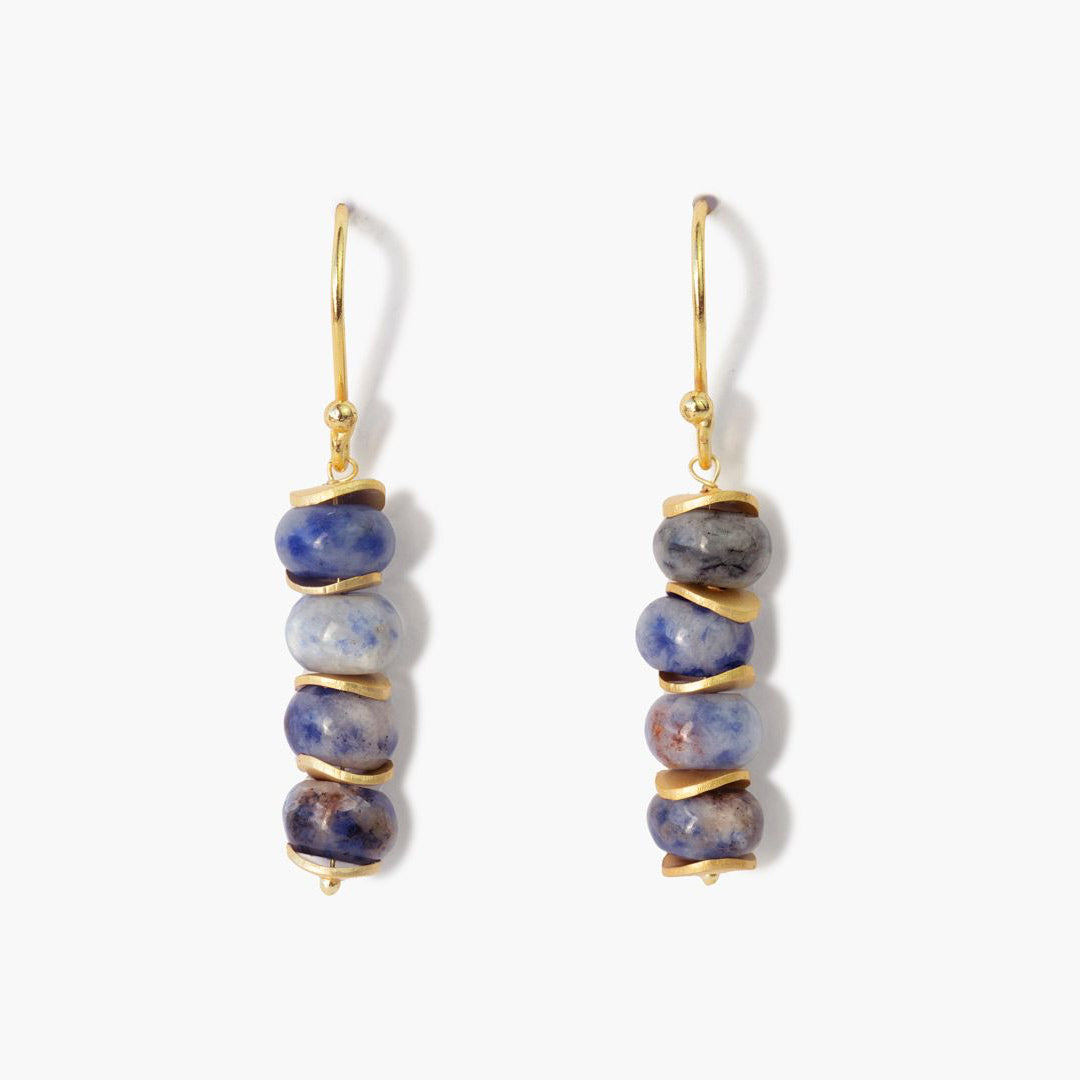 Pendientes Mosaico de acabado dorado con piedras en tonos azules y grises, fotografiados sobre fondo blanco con sombra suave
