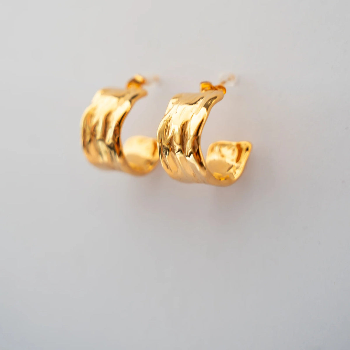 Semi aros martillados dorados vistos de lado sobre fondo claro