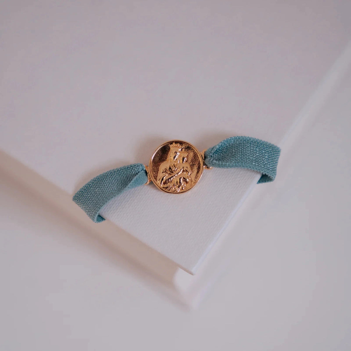 Pulsera escapulario con cinta elástica azul apoyada sobre un libro