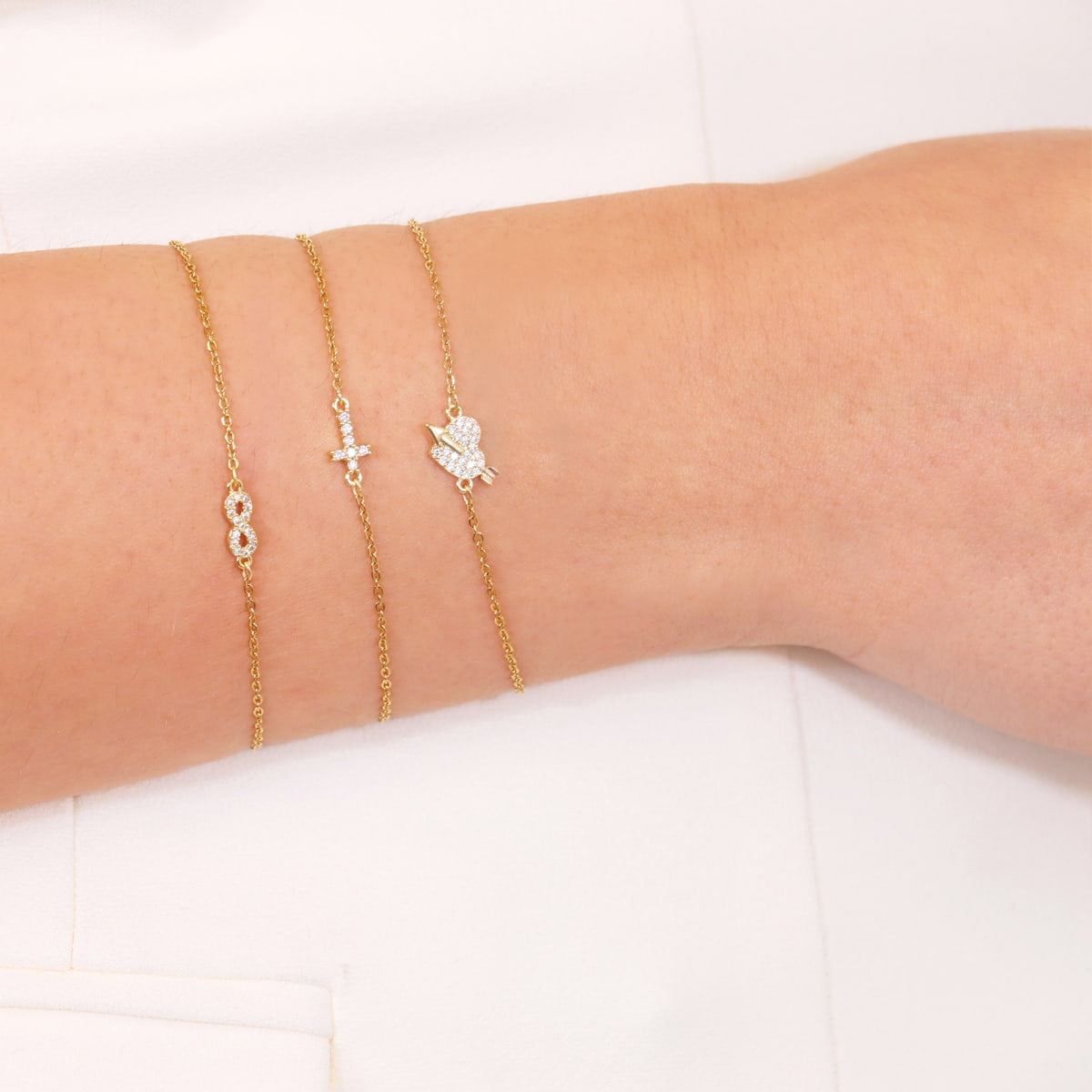 Pulsera Cruz Mini de Acero 316L puesta en la muñeca con otras pulseras finas