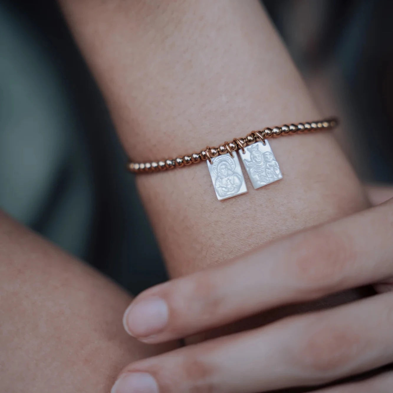 Pulsera Faith puesta en la muñeca, con los dos escapularios de efecto nácar colgando