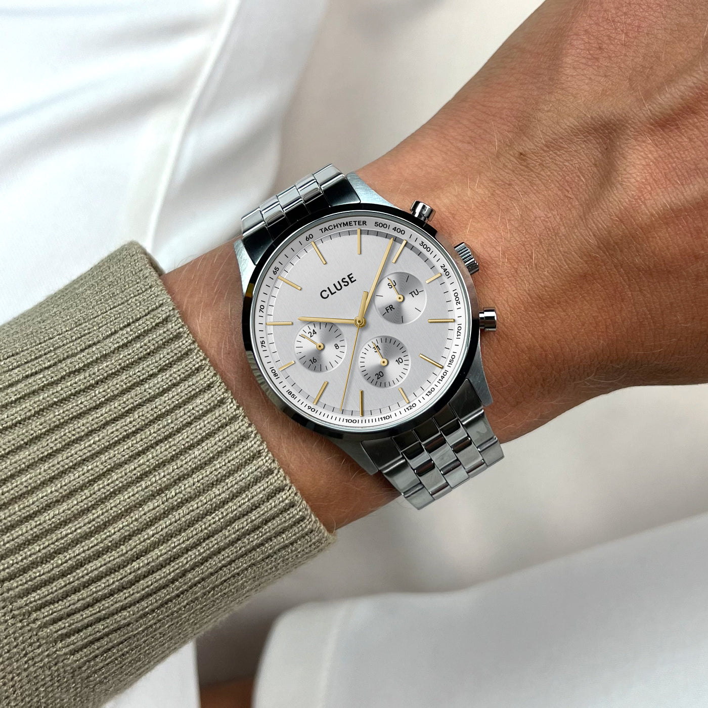 Reloj Cluse Anthéor en acero plateado y dorado con subesferas de día, hora y fecha. Detalle de vista en la muñeca