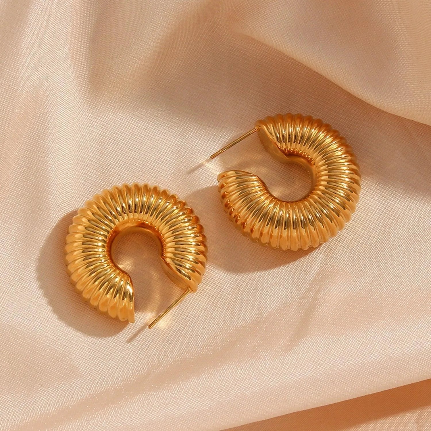 Aros rayados en acero con baño de oro vistos de cerca, diseño moderno y versátil